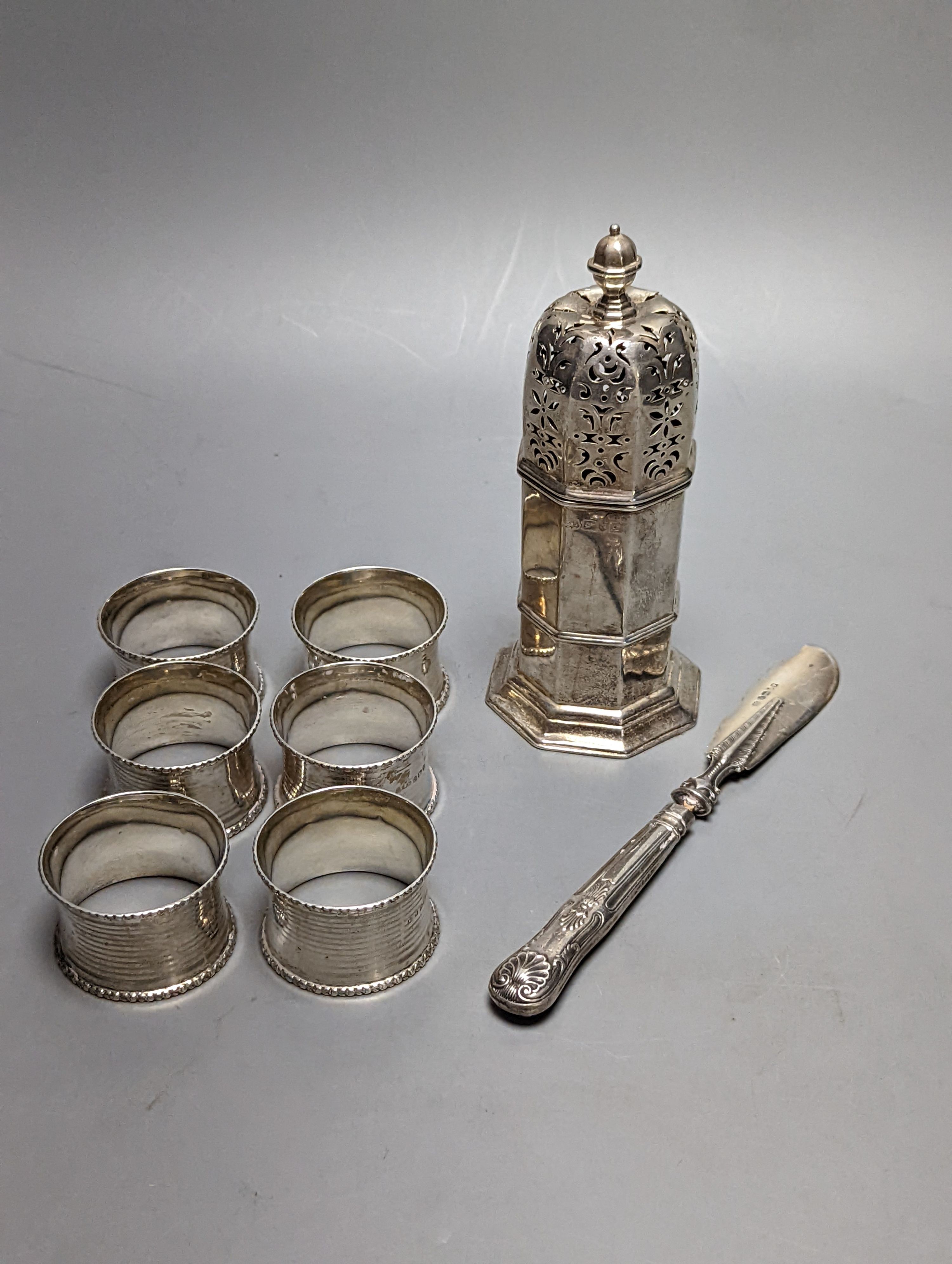A set of six George V silver napkin rings, Birmingham, 1915, a silver sugar caster and silver butter knife.